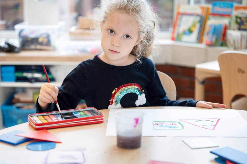 A picture of a young girl in art class, painting a picture.