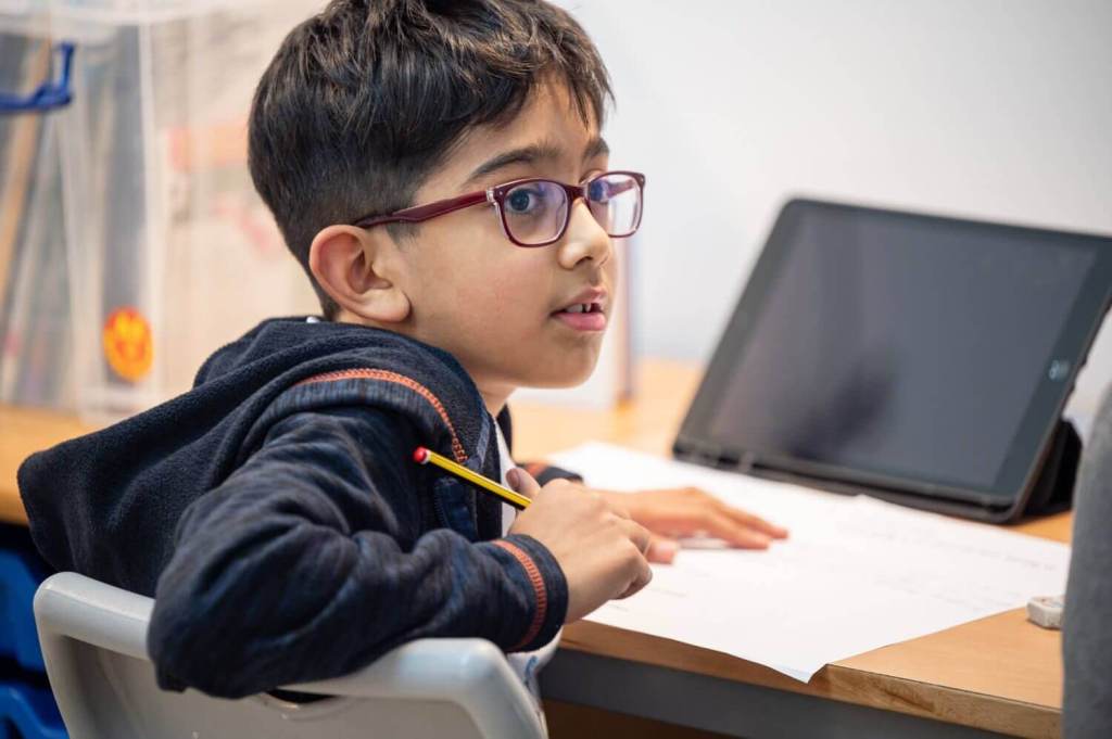 A young EC student turned on his chair paying attention to someone, whist holding a pencil