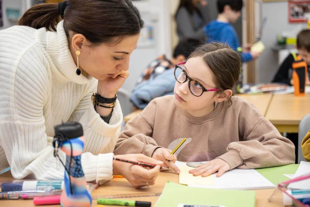 A female student looking up to her teacher as she helps