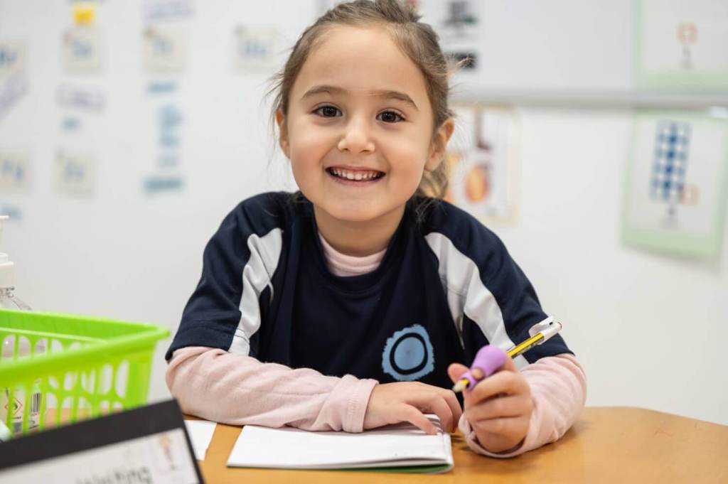 Child smiling with pencil and book