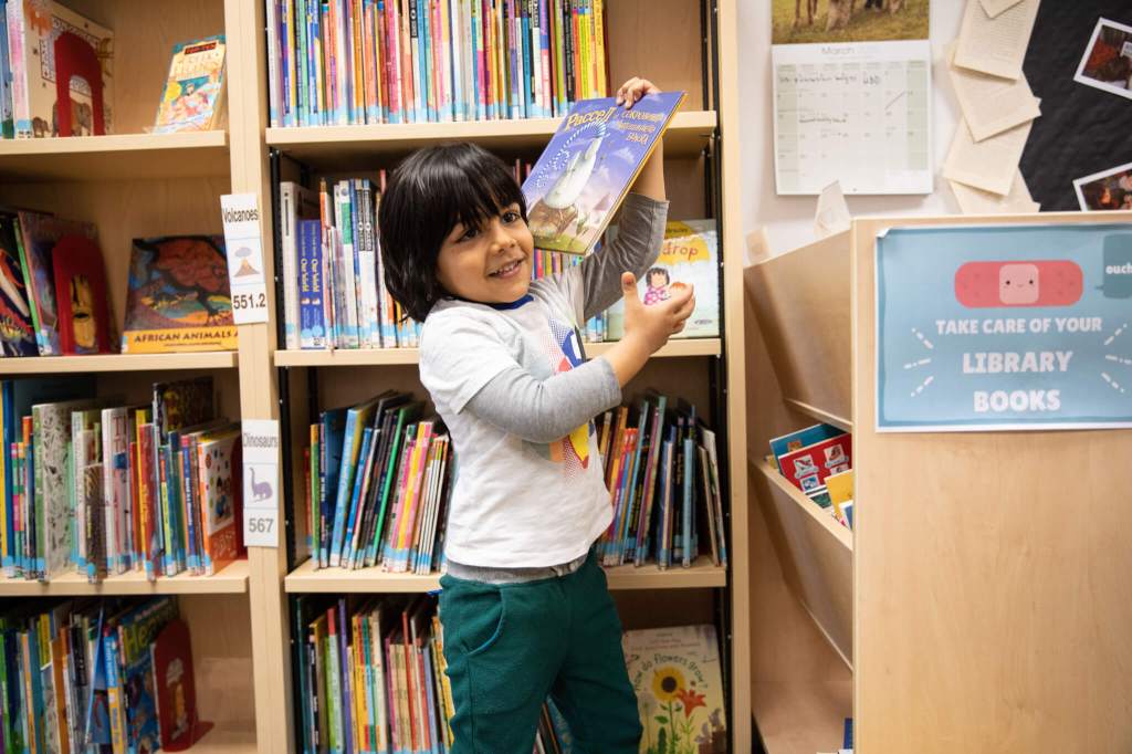 A young EC student holding a book after choosing it from the book shelf.